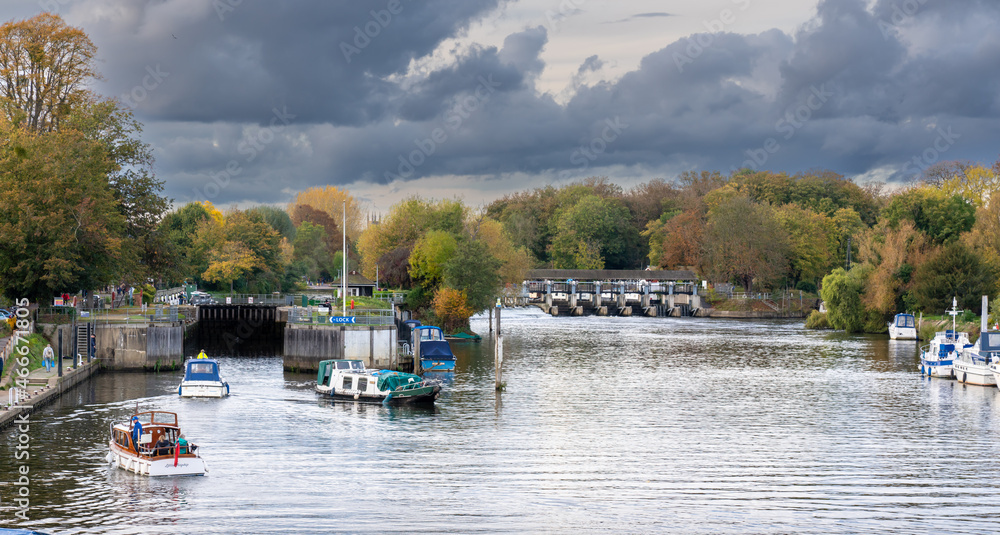 HAPTON COURT, LONDON, UK - Circa 2021 October Boats coming out of a lock on the river Thames with a moody sky