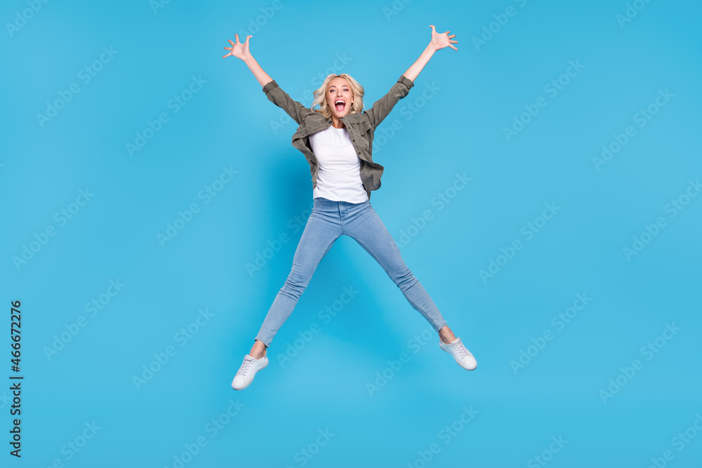 Full length body size photo amazed woman jumping up careless happy isolated pastel blue color background Full length body size photo amazed woman jumping up careless happy isolated pastel blue color background