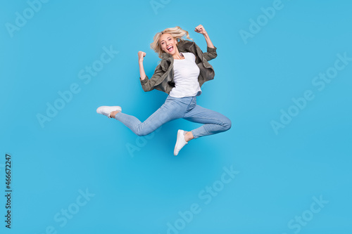 Full length body size photo woman jumping up showing strong hands isolated pastel blue color background