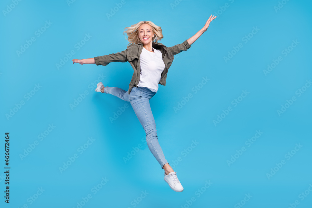 Full length body size photo happy woman jumping up stretching isolated pastel blue color background Full length body size photo happy woman jumping up stretching isolated pastel blue color background