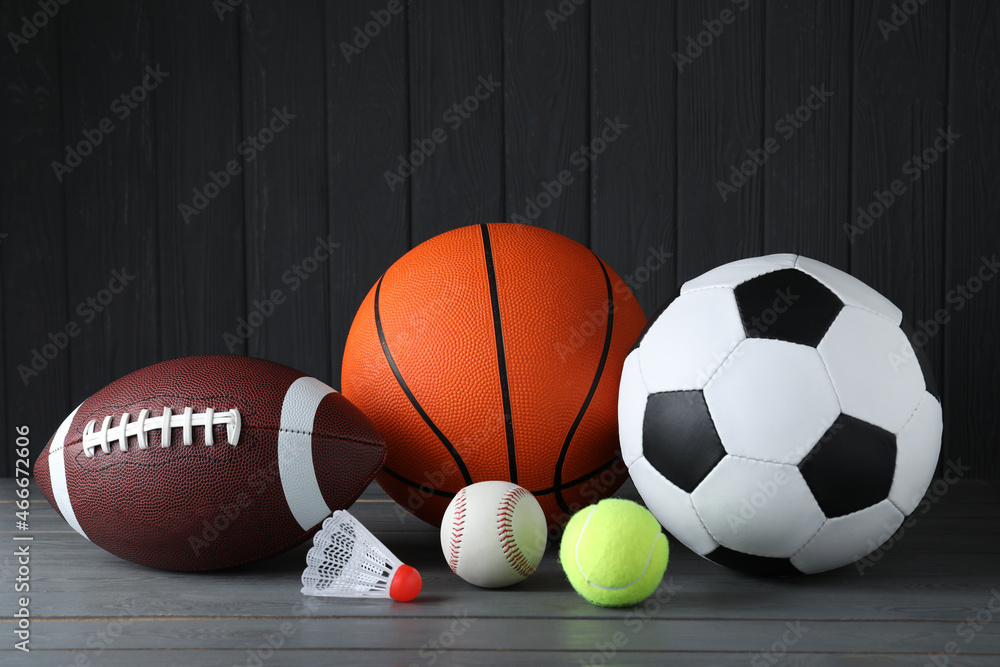 Set of different sport balls and shuttlecock on grey wooden table