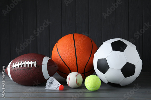 Set of different sport balls and shuttlecock on grey wooden table