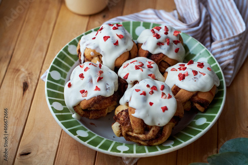 Cinnamon rolls with cream and freeze-dried strawberries, round yeast rolls. Side view, wooden background.