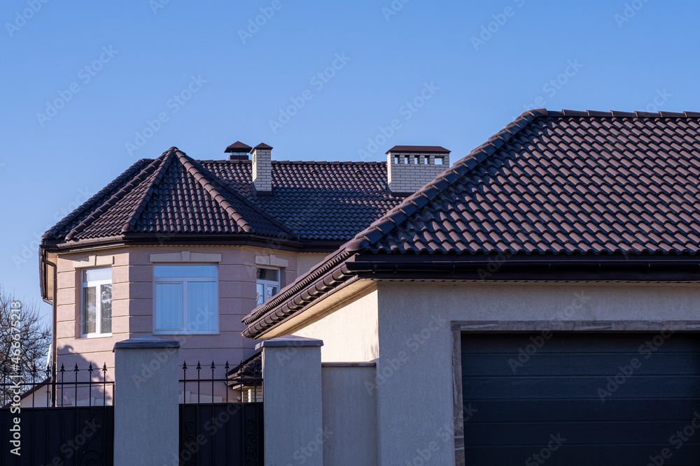 The roof is brown metal tiles, a large house with a garage.