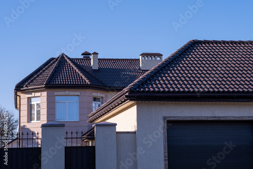 The roof is brown metal tiles, a large house with a garage.