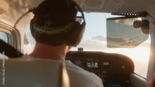 Man flying a small Cessna plane during the sunrise.