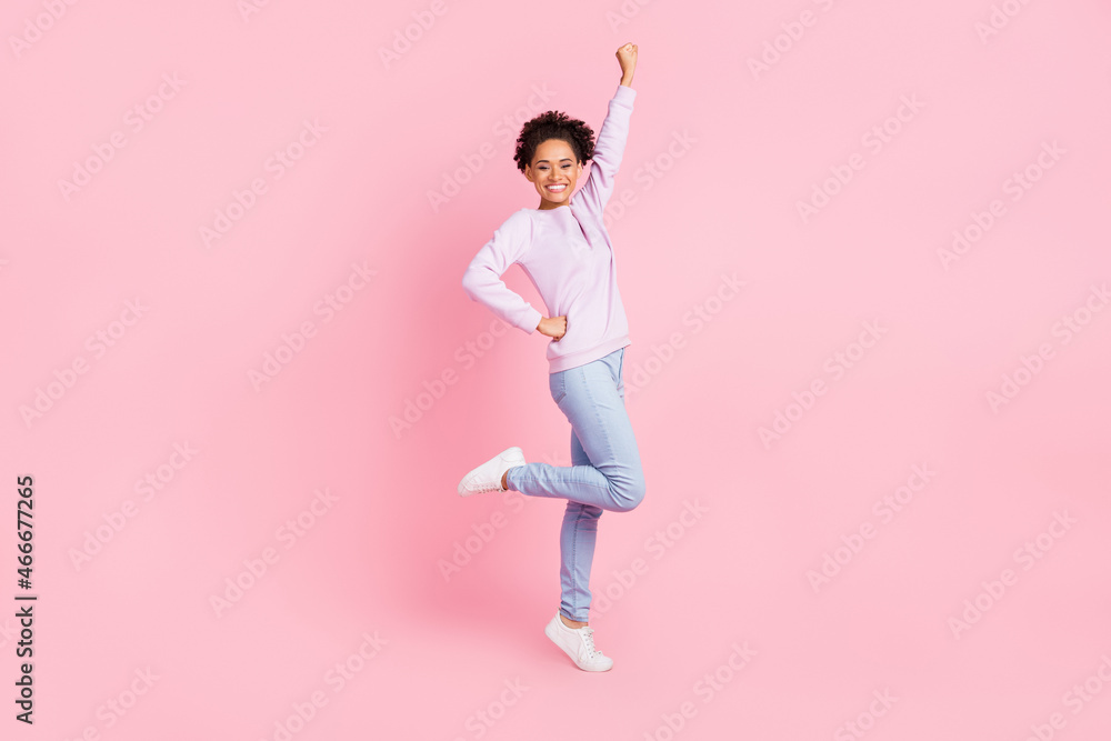 Full size photo of young good mood cheerful excited afro girl raise fist in victory triumph isolated on pink color background Full size photo of young good mood cheerful excited afro girl raise fist in victory triumph isolated on pink color background