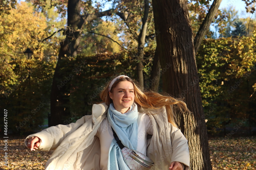 a young girl whirls in the park in late autumn, splashing in the last sun among the falling yellow foliage a young girl whirls in the park in late autumn, splashing in the last sun among the falling yellow foliage