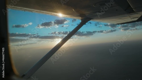 Man flying a small Cessna plane during the sunrise.