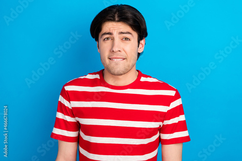 Photo of attractive doubtful young guy dressed red t-shirt biting lip isolated blue color background