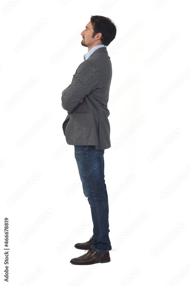 side view of a man with blazer and jeans, arms crossed looking up on white background side view of a man with blazer and jeans, arms crossed looking up on white background