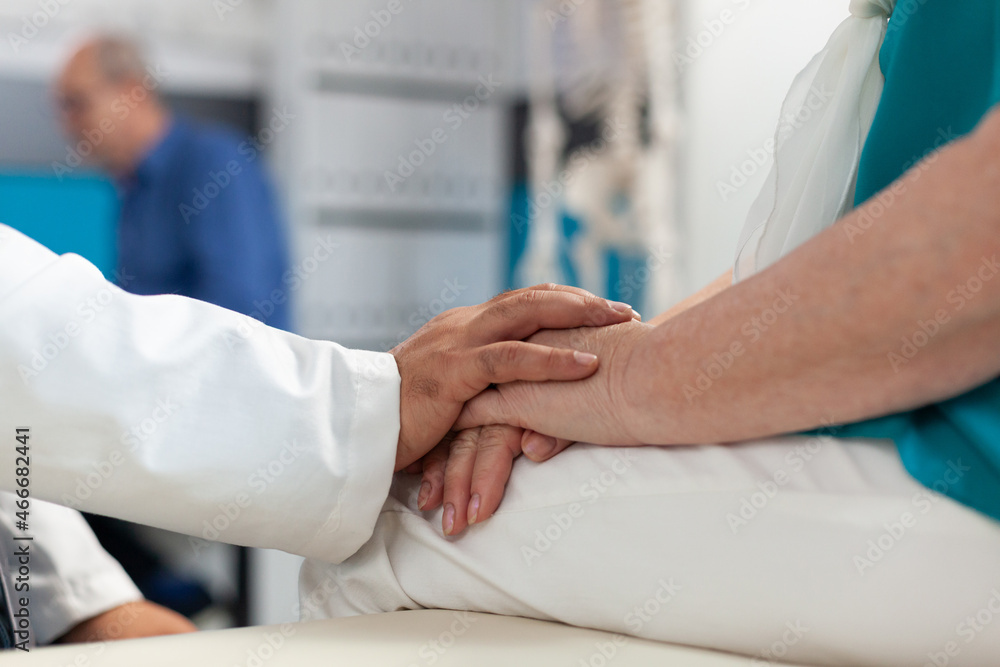 Close up of doctor supporting retired woman with physical pain, holding hands of patient to assure recovery and remedy. Medic comforting aged person with arthritis at physiotherapy Close up of doctor supporting retired woman with physical pain, holding hands of patient to assure recovery and remedy. Medic comforting aged person with arthritis at physiotherapy