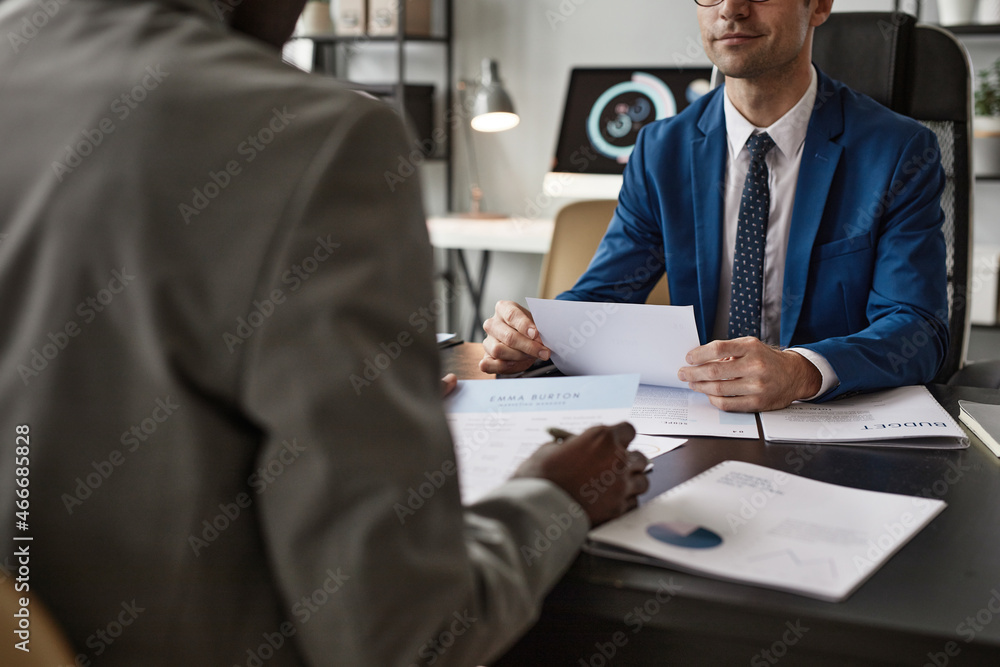 Cropped shot of two businessmen reading documents during meeting in office, copy space Cropped shot of two businessmen reading documents during meeting in office, copy space