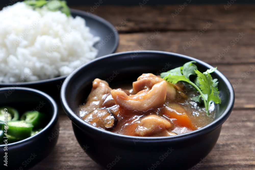 Chicken stew in gravy sauce or kao na kai in Thai language is served on the wooden table with jasmine rice and green chilli for breakfast in the Thai traditional restaurant