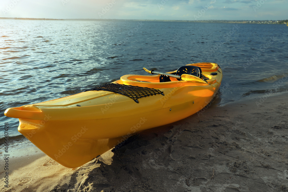 Beautiful modern yellow kayak with paddle on beach Beautiful modern yellow kayak with paddle on beach