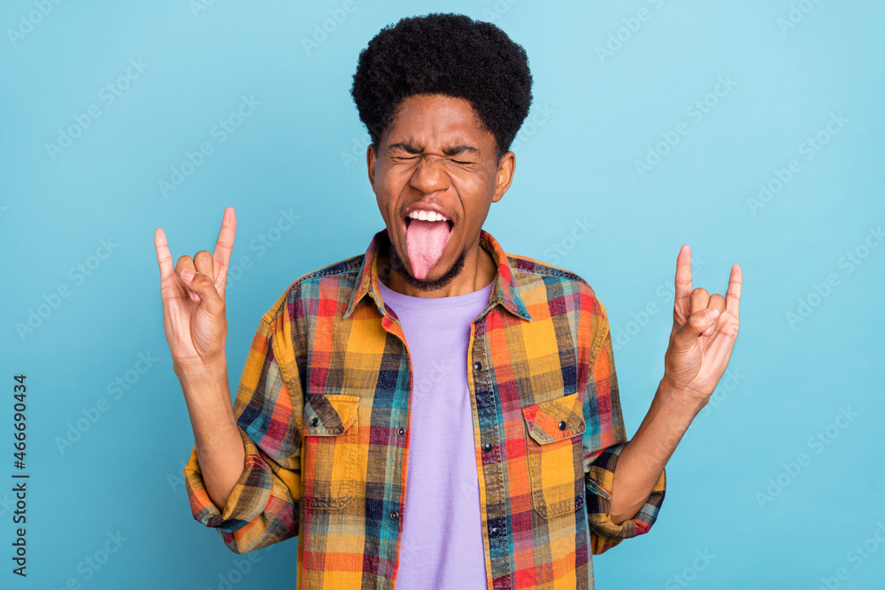 Photo of funky millennial brunet guy show rock sign wear yellow shirt isolated on blue color background Photo of funky millennial brunet guy show rock sign wear yellow shirt isolated on blue color background