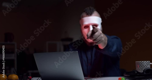 A man in a white mask incognito points a threatening finger at the camera. Computer cracker. Hacker.