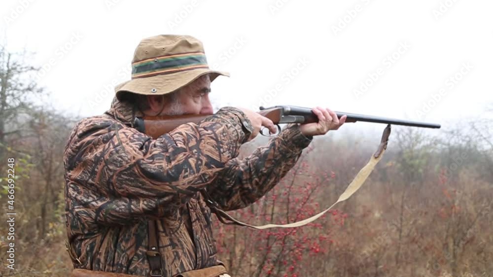 hunter man with gray beard in hunter suit load cartridges in a double-barreled rifle and makes aiming wiring hunter man with gray beard in hunter suit load cartridges in a double-barreled rifle and makes aiming wiring