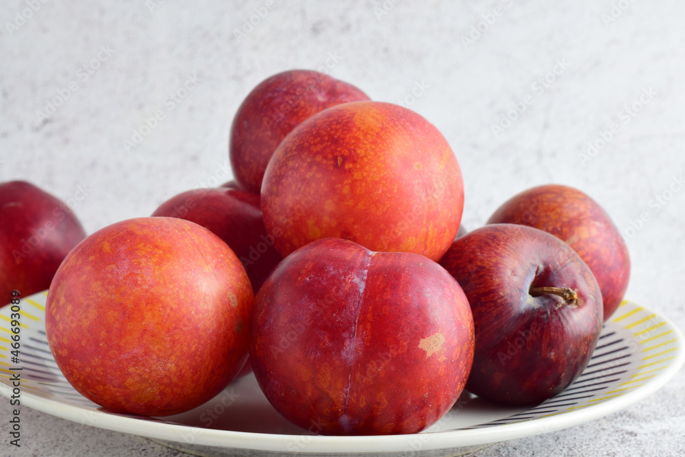 Close up, red plums on porcelain plate and stone background. Close up, red plums on porcelain plate and stone background.