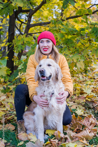 Woman walking with her retriever among yellow leaves