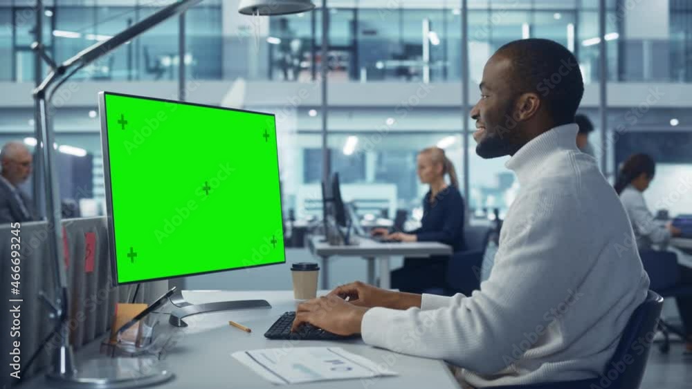 Diverse Modern Office: Handsome Black Businessman Using Desktop Computer with Green Screen Mock Up Display. Manager Working on e-Commerce App Development, Project Marketing, Big Data Analysis Diverse Modern Office: Handsome Black Businessman Using Desktop Computer with Green Screen Mock Up Display. Manager Working on e-Commerce App Development, Project Marketing, Big Data Analysis