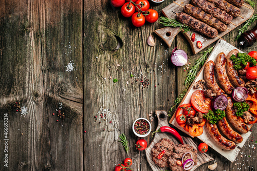 Various kinds of grilled gourmet meats on a rustic wooden table. Barbecue menu. banner, menu, recipe place for text, top view