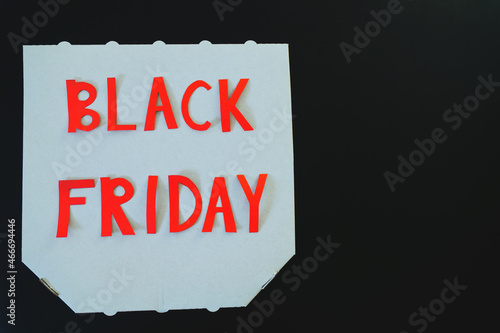 Inscription "black friday" on a white cardboard pizza box on black background. Copy space, top view, flat lay. Creative holiday flyer. Sale. 