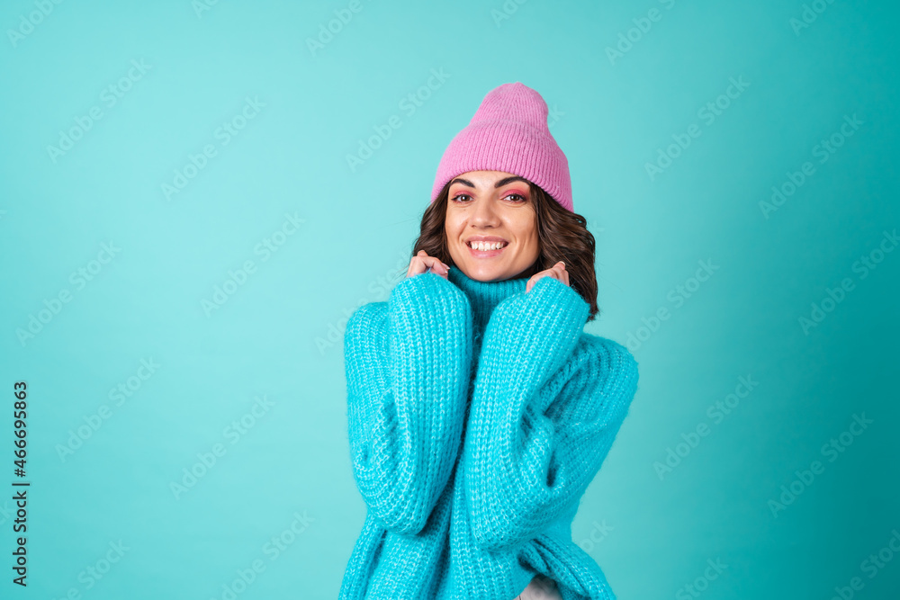 Cozy portrait of a young woman in a knitted blue sweater and a pink hat with bright makeup Cozy portrait of a young woman in a knitted blue sweater and a pink hat with bright makeup