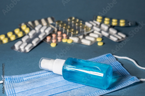 Pandemic prevention. Medical masks antiseptic spray teblets vitamins on blue background photo