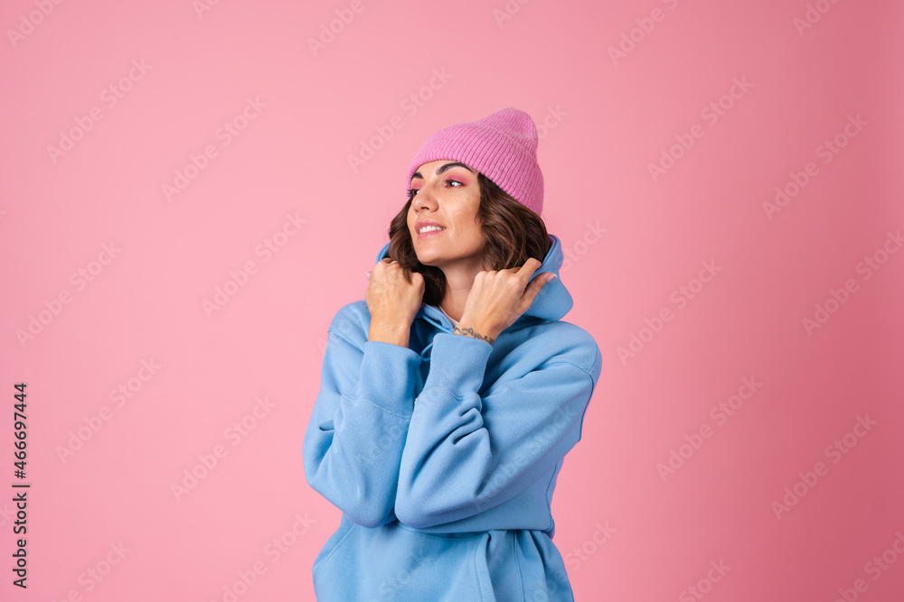 Young woman in a cozy suit on a fleece, a hoodie and pants, on a pink background, a knitted hat on her head Young woman in a cozy suit on a fleece, a hoodie and pants, on a pink background, a knitted hat on her head
