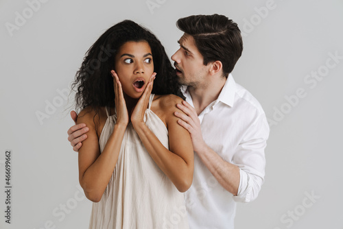 European unshaven man hugging her shocked black girlfriend