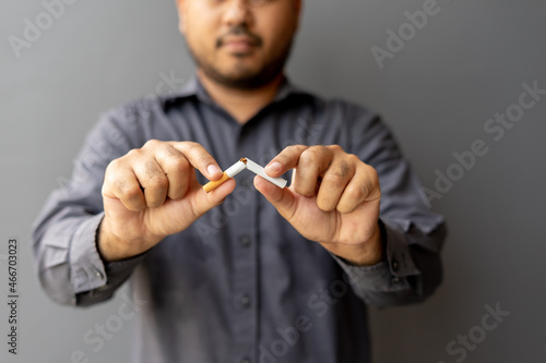 Portrait young man holding broken cigarette in hands. Happy male quitting refusing smoking cigarettes. Quit bad habit, Stop smoking cigarettes, health care concept. No smoking campaign.
