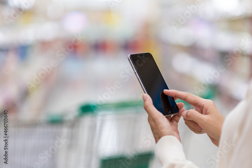 Hands woman using smartphone and shopping in a supermarket. Shopping concept