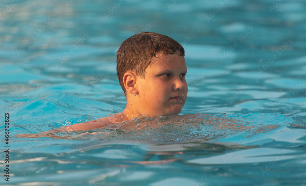 The boy swims in the pool