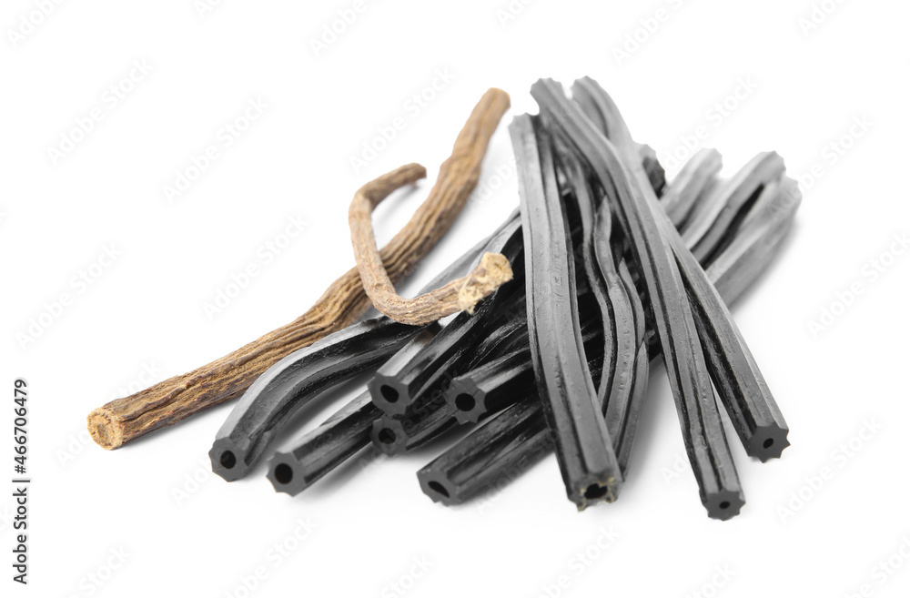Tasty black candies and dried sticks of liquorice root on white background Tasty black candies and dried sticks of liquorice root on white background