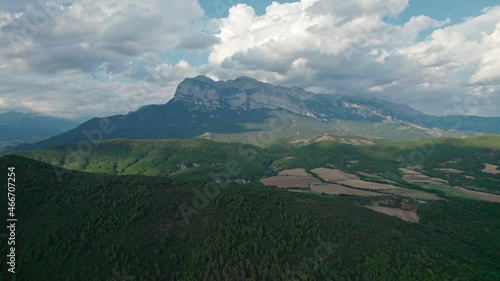 A great mountain, a rock protruding on a plateau in the Pyrenees mountains. Spectacular view of the mountain range from a drone with huge cumulus clouds in the background.