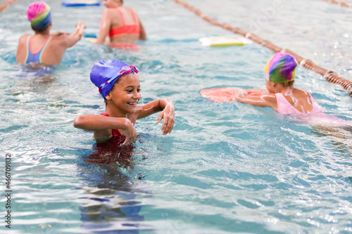 Little girl having fun in swimming pool with friends