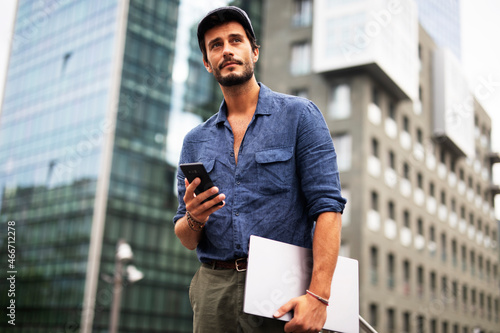 Young stylish man using the phone outdoors. Fashion happy businessman outdoors..