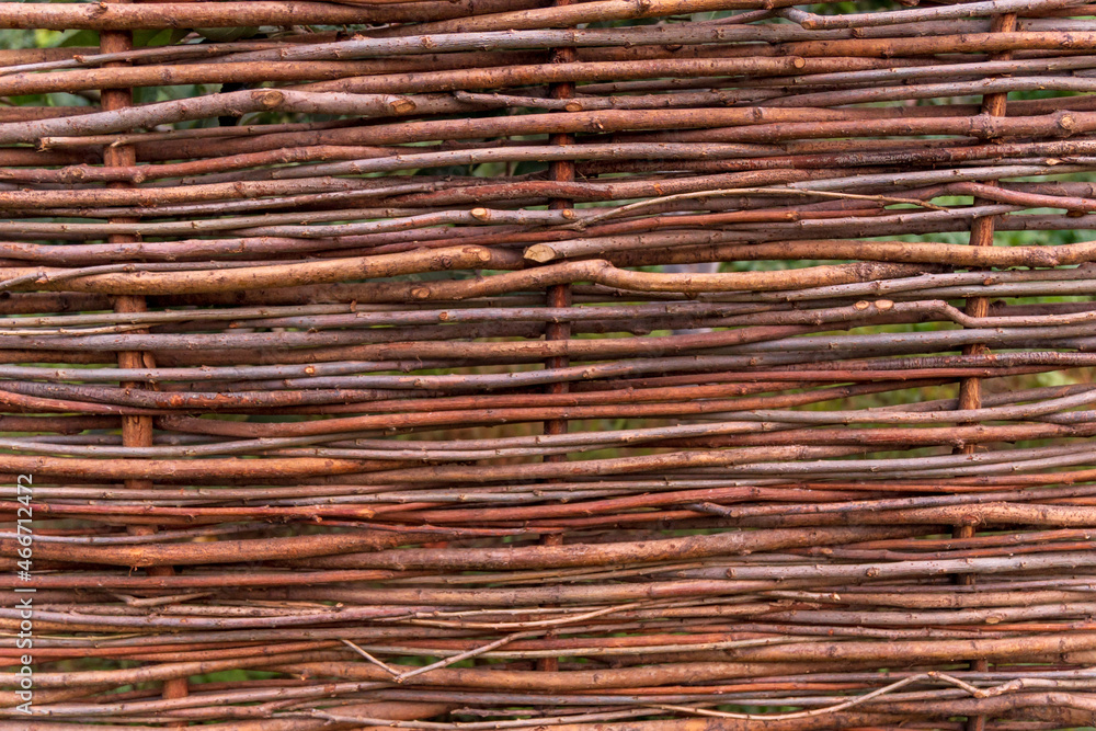 Close-up fence made of wooden rods. Wicker fence made of twigs. Natural fence made of branches. Background Texture Close-up fence made of wooden rods. Wicker fence made of twigs. Natural fence made of branches. Background Texture