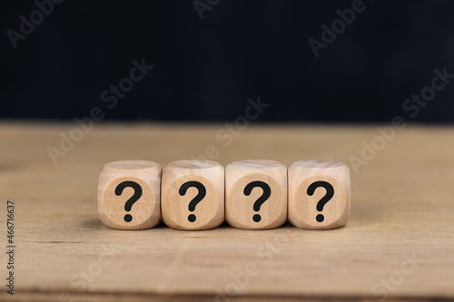 Wooden cube with Question mark icon on wooden table.