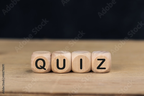 Wooden cube with the word QUIZ on wooden table.