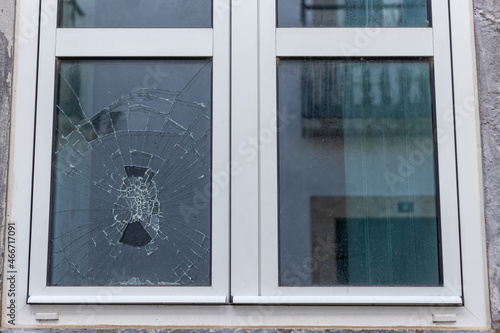 Cracked glass in a plastic vacuum window frame. A damaged window due to vandalism, natural disaster, or accident.