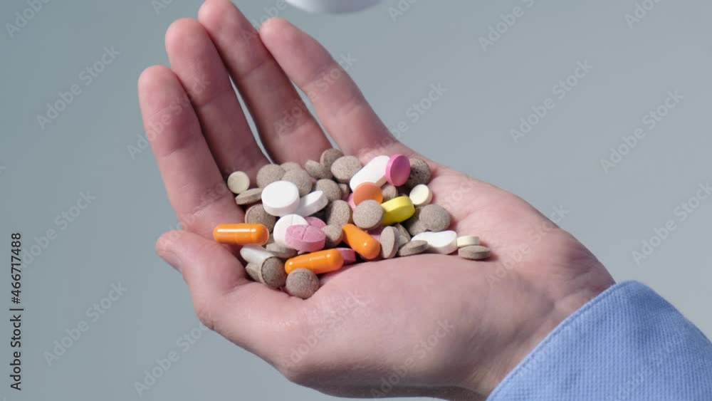 Colored pills falling into a man's palm, close-up. Pharmaceutical drugs Colored pills falling into a man's palm, close-up. Pharmaceutical drugs