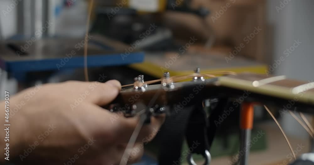Guitar tech takes off the old strings from the guitar tuners, changing the strings on the acoustic guitar, 4k 60p 10 bit Guitar tech takes off the old strings from the guitar tuners, changing the strings on the acoustic guitar, 4k 60p 10 bit
