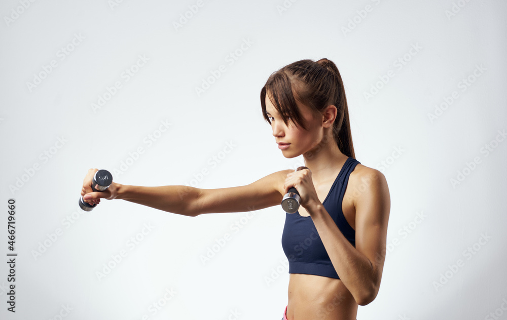 Fototapeta premium athletic woman fitness exercise dumbbells in the hands of Strong light background