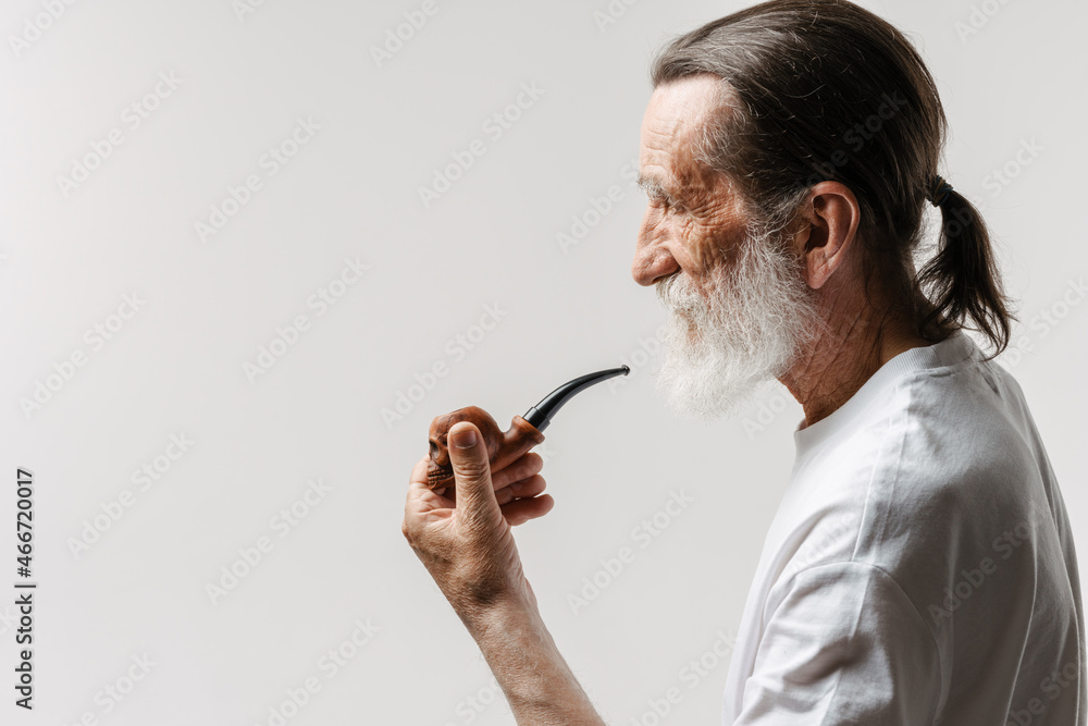 European senior man looking aside while posing with smoking pipe European senior man looking aside while posing with smoking pipe