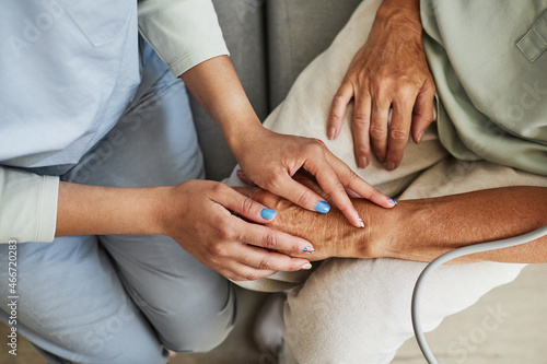 Close up of female nurse holding hands with senior woman in retirement home  copy space