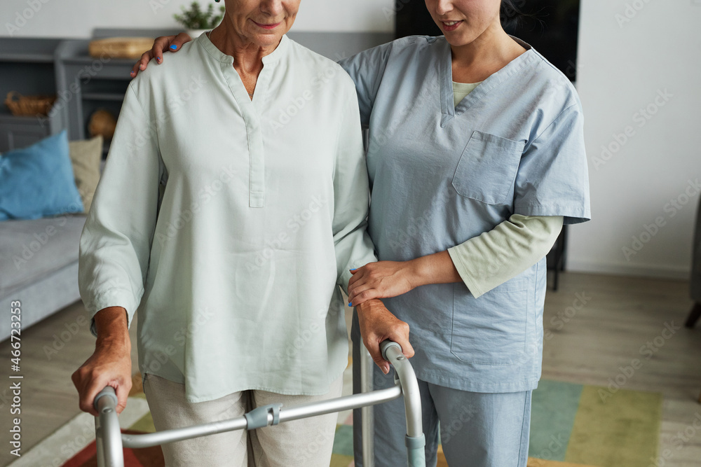 Cropped shot of female nurse helping senior woman using mobility walker in retirement home, copy space