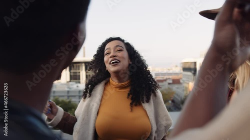 Multi-cultural female socializing with a diverse group of adult friends at rooftop party. Chatting lightheartedly at dusk. High quality image. photo