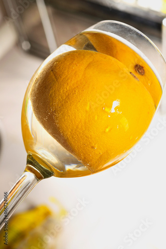 dynamic shooting angle from below on a glass with a whole orange in a drink in a glass. Refreshing lemonade concept.
